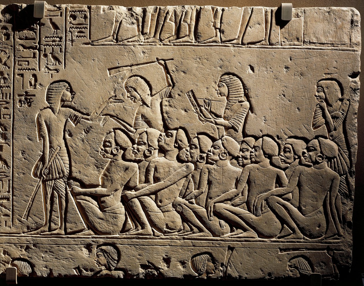 En grupp negroida fångar omringade av vakter beväpnade med klubbor medan en skriftlärd skriver en rapport, relief från Horemhebs grav i Saqqara av Egyptian 18th Dynasty
