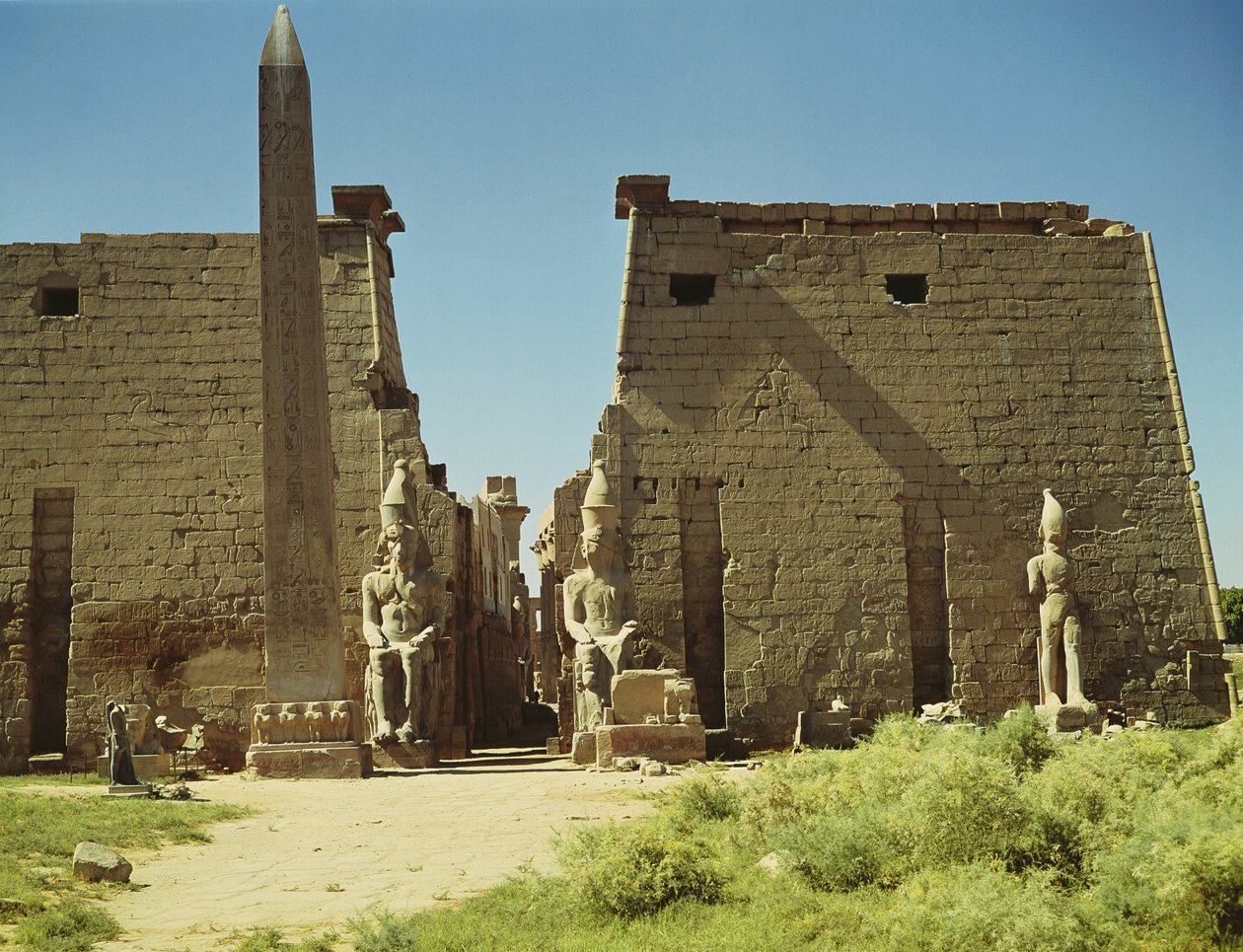 Fasad och första pylon med två sittande statyer av Ramesses II och den återstående obelisken av Egyptian 19th Dynasty