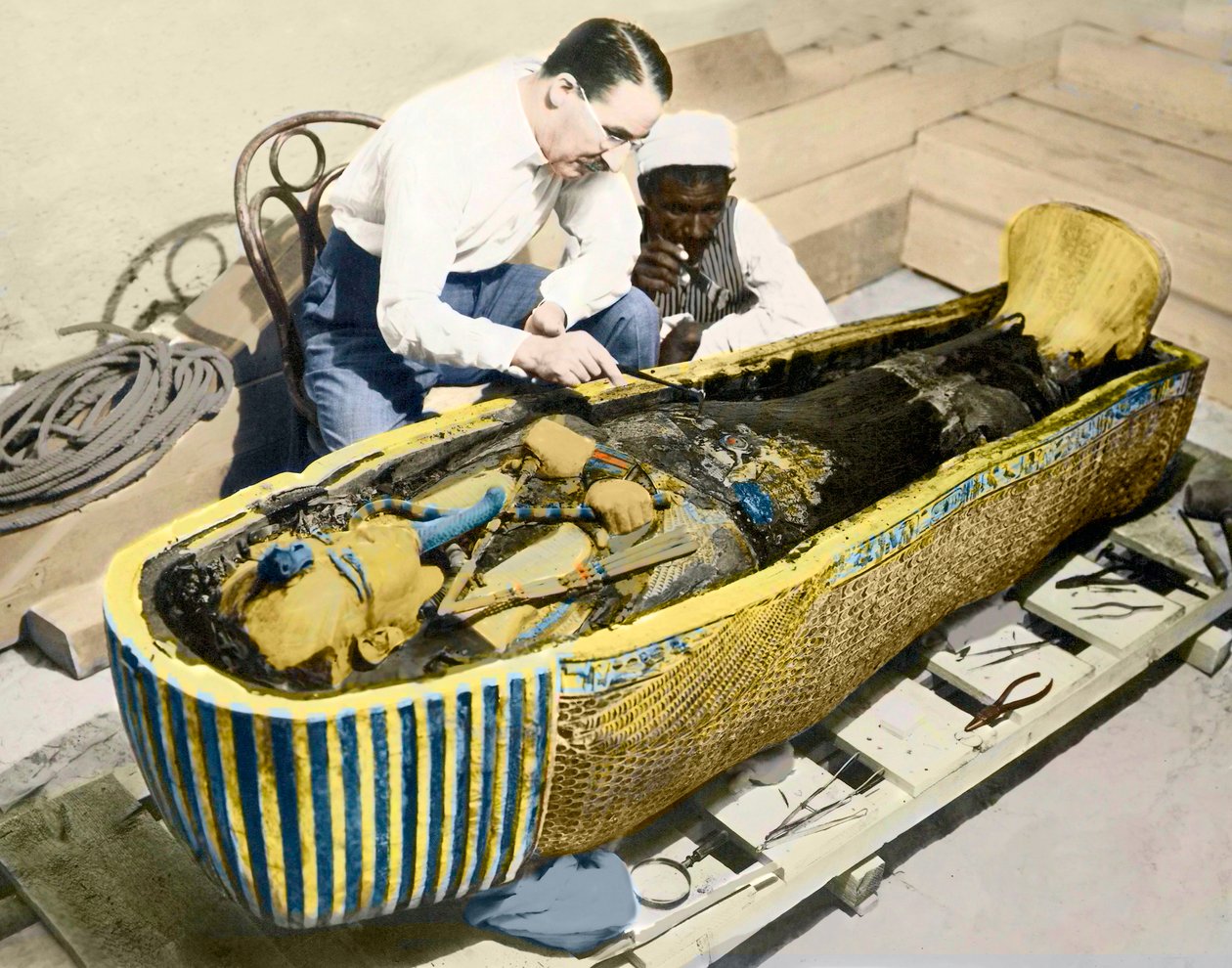 Egypten-1922: Den engelske arkeologen Howard Carter (1873-1939) och en egyptisk assistent som undersöker kung Tutankhamons sarkofag. av English Photographer