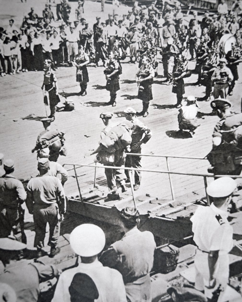 Kiltpipare spelar i land från 1:a bataljonen Argyll och Sutherland Highlanders från HMS Ceylon vid Pusan, 29 augusti 1950 (s/v foto) av English Photographer