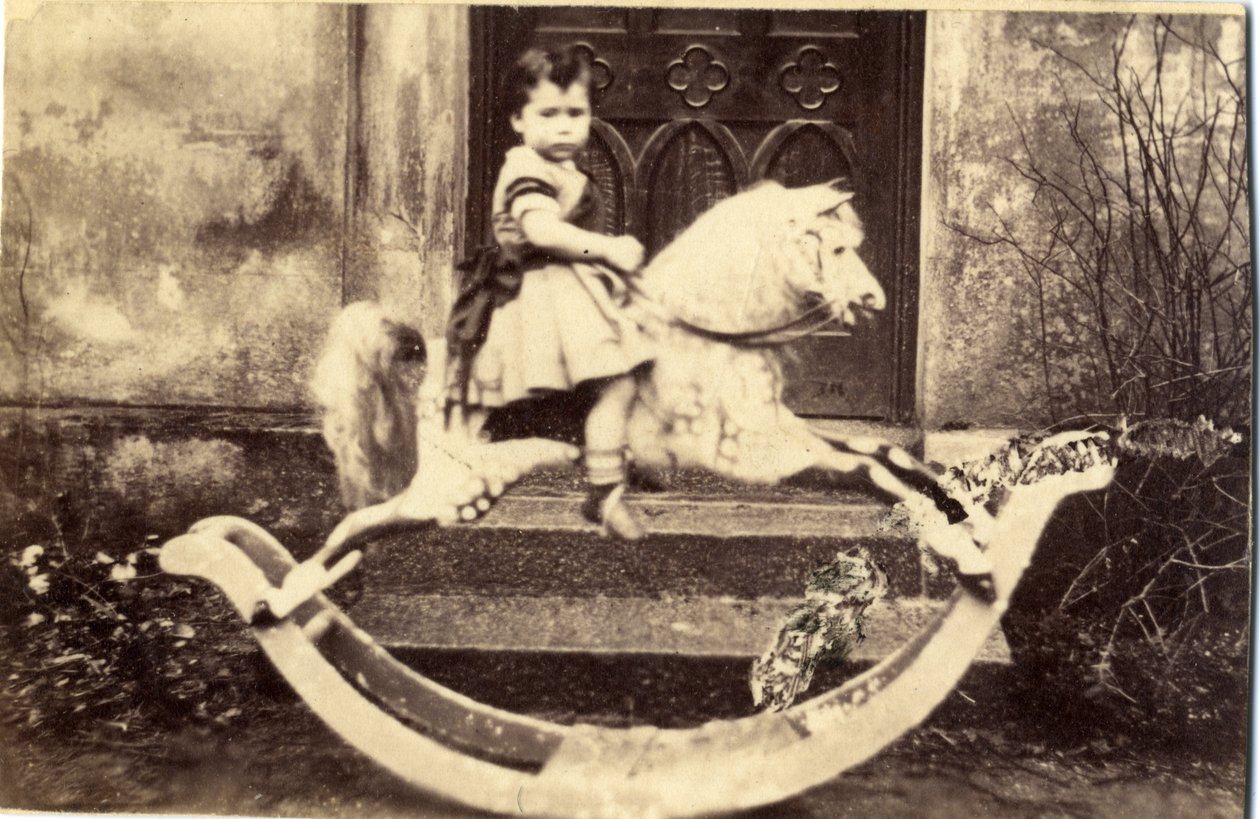 Liten flicka på en stor gunghäst i en trädgård, 1860-tal (albumintryck) av English Photographer