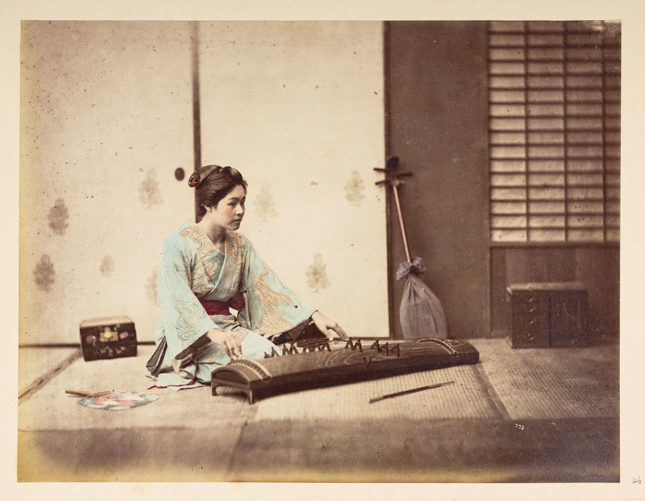 Sjungande tjejer [Japan], Studioporträtt av en ung japansk kvinna som sitter på en tatamimatta och spelar ett stränginstrument,  Fotograf: Okänd  Lucas Collection: Fotografiskt rekord från Charles James och Morton P, Lucas världsturné av English Photographer