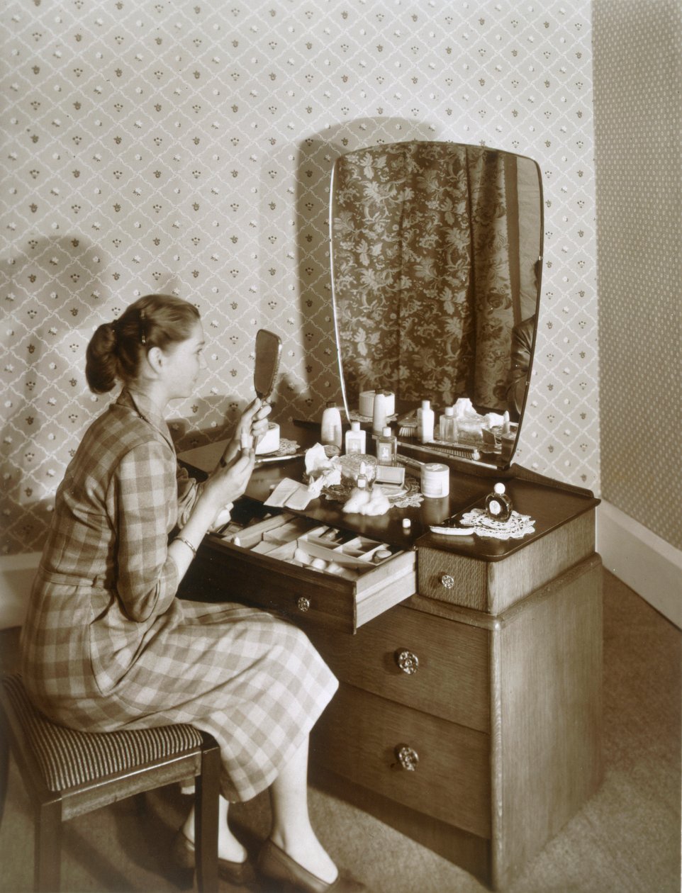 Kvinna vid hennes toalettbord, c1955. av English Photographer