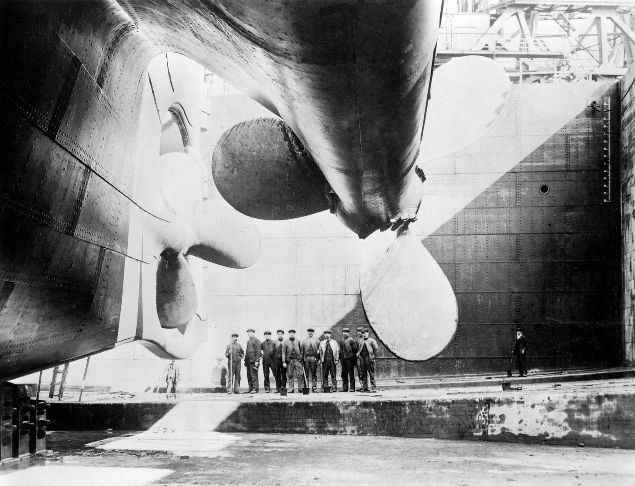 Arbetare som står under en av propellrarna på Titanic, 31 maj 1911. av English Photographer
