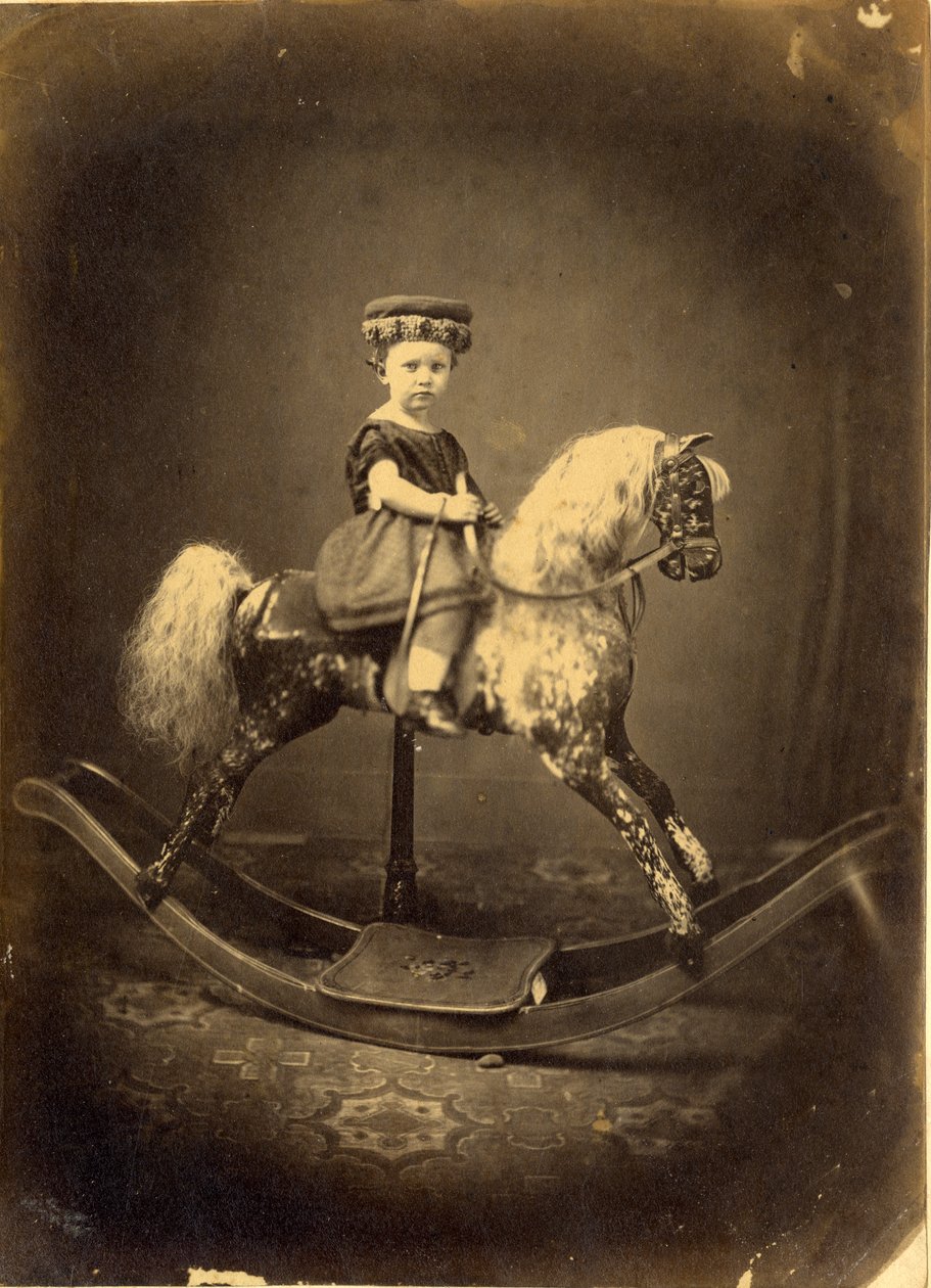 Ung flicka sittande på en gunghäst av English Photographer
