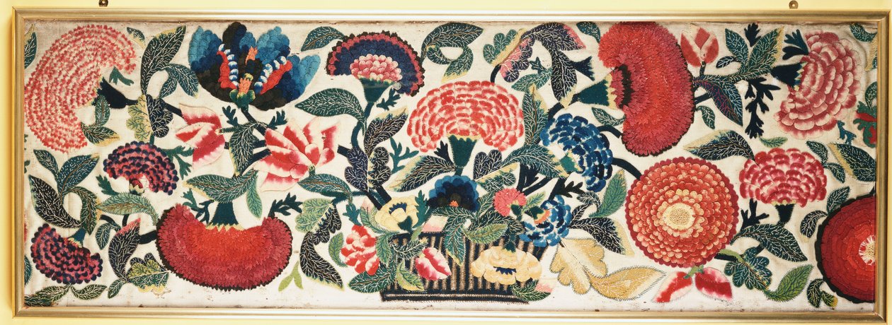 En filt- och applikationspanel med broderade sidenhöjdpunkter som visar nejlikor, tulpaner och andra blommor som svämmar över från en korg mot en mald elfenbensull, ca 1730-40 av English School