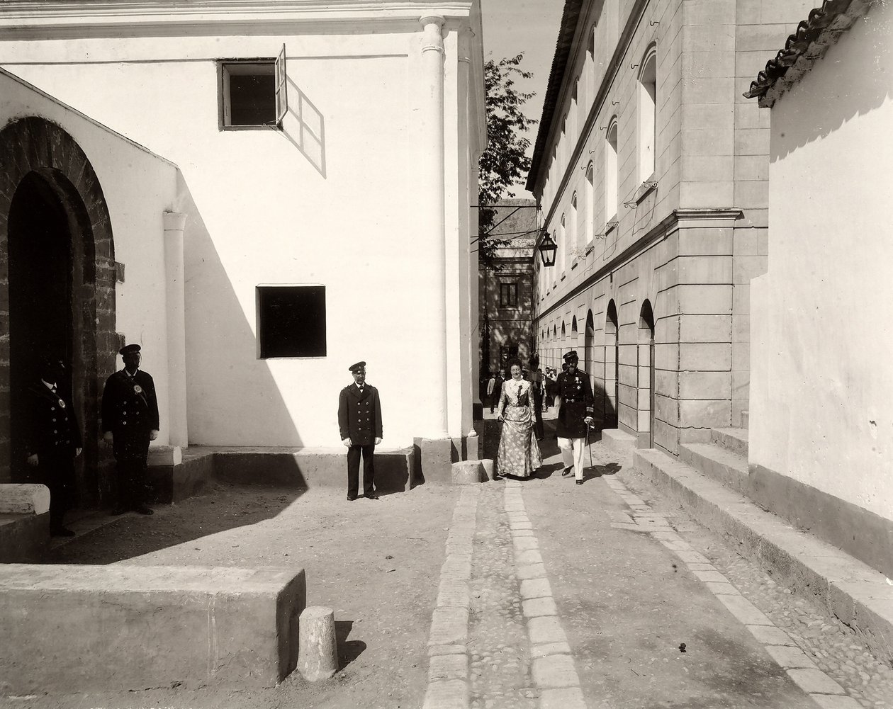 Män i uniform som följer med en elegant klädd kvinna mot kyrkan på gården Lo Zucco, Sicilien, 1900 av Eugenio Interguglielmi