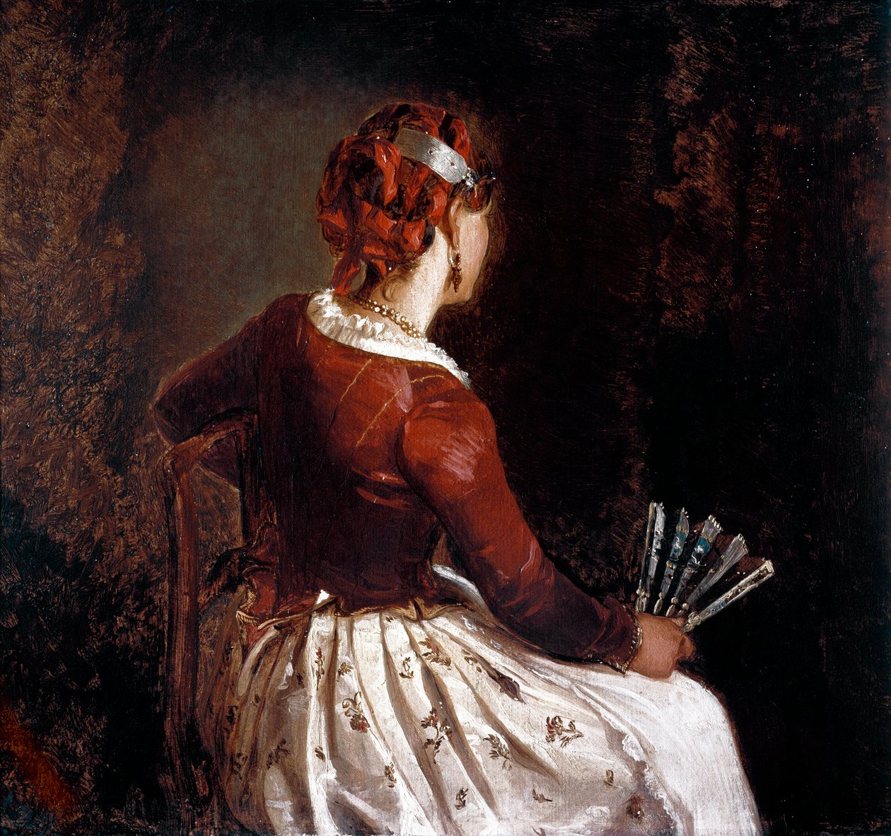 Kvinnan har fläkten. Porträtt av en sittande kvinna vänt tillbaka iklädd ett förkläde, en kjol med blommor och röda band i håret och en solfjäder i handen. Målning av Filippo Palizzi (1818-99). Roma, Galleria d