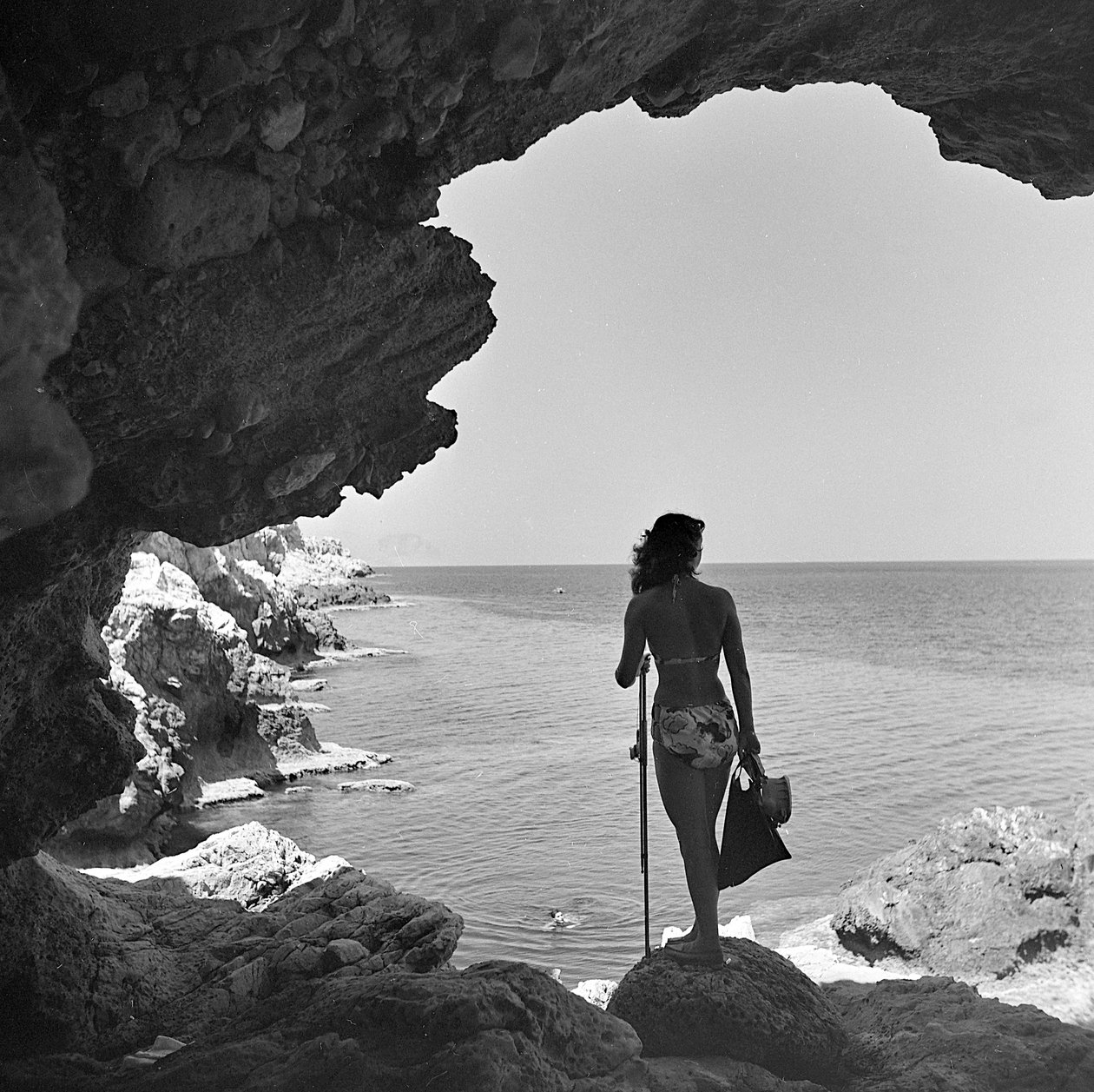 Badare på klippan som tittar ner mot havet nära byn Aspra, nära Palermo, Sicilien, ca 1950 (svartvitt foto) av Fosco Maraini