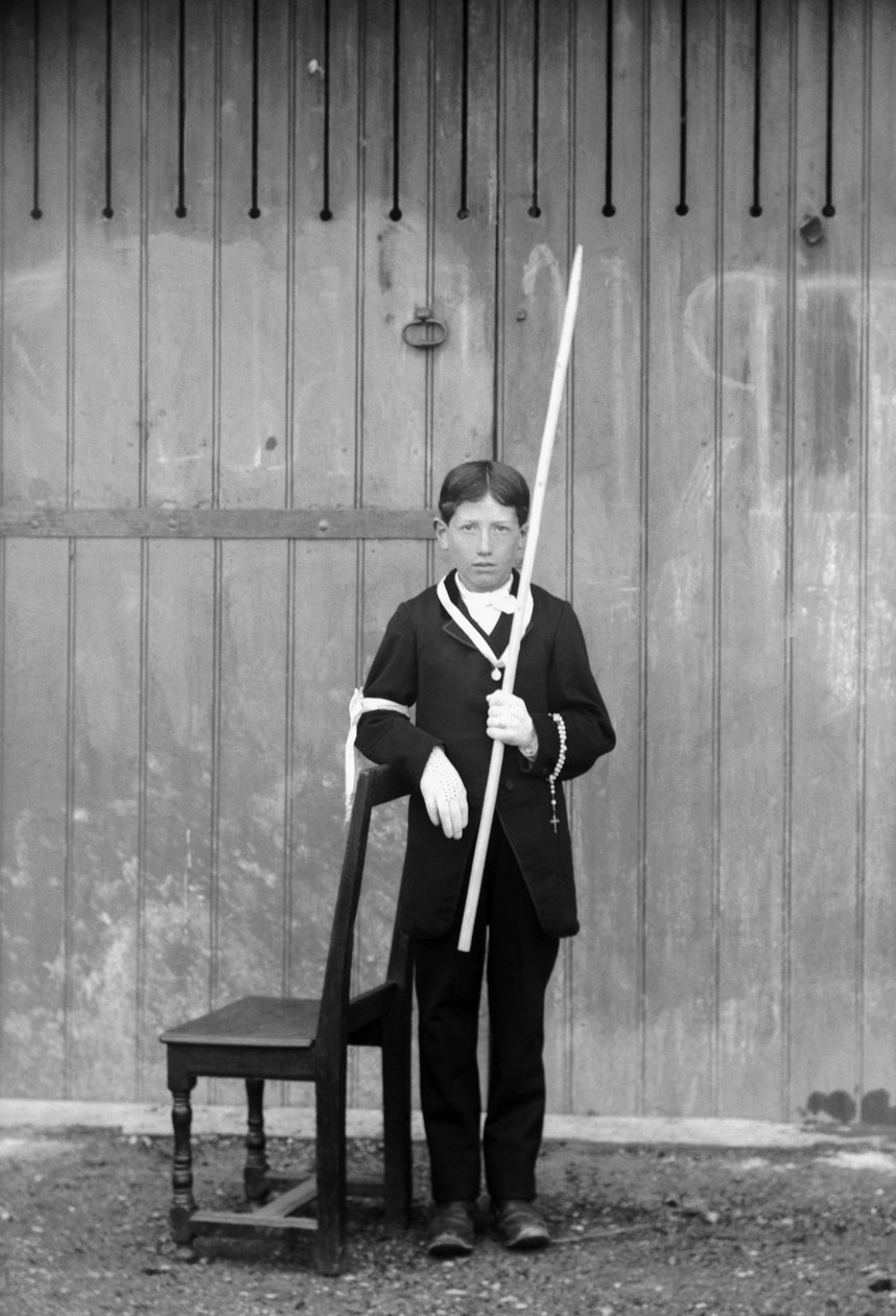 Första kommunikanten, i vit kostym och handskar, med medaljer, radband, vit spetsmanschett och bär ett mycket långt ljus, nära Bourmont i Haute-Marne (Haute Marne), cirka 1880. Fotografi. Ducos samling. av French Photographer