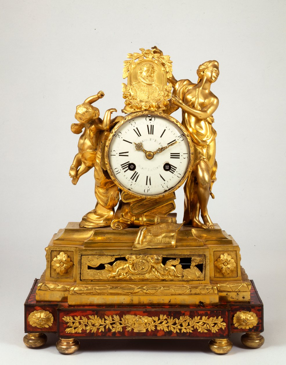 En sen Louis XV ormolu mantelklocka med en profilmedaljong av Henri IV som innehas av Venus av French School