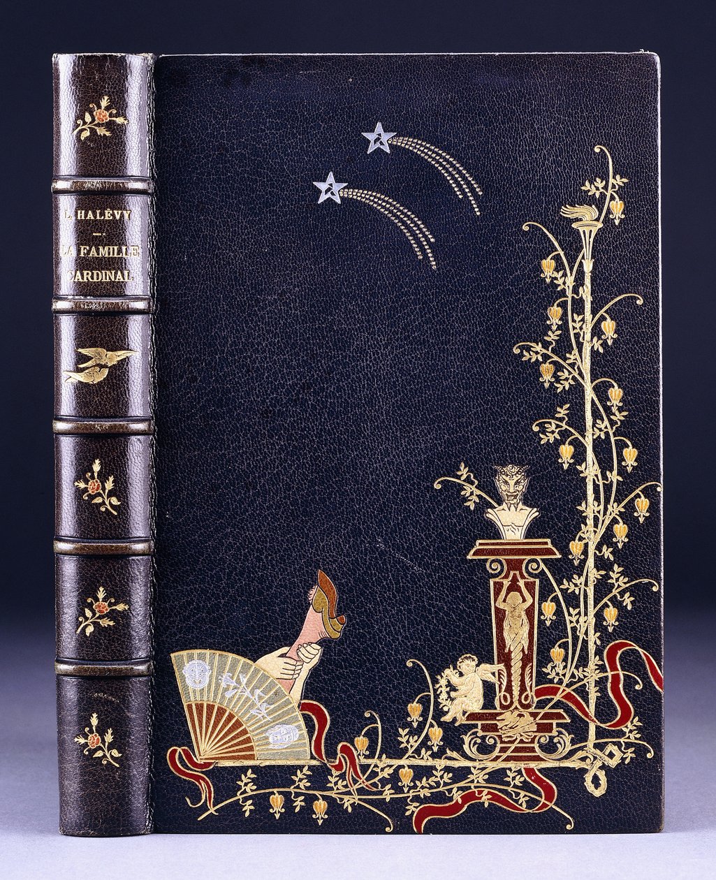 Övre bokomslag med två stjärnfall, en fackla, lövverk, faun på piedestal, putto och ett ben bakom en fläkt, 1893 av French School