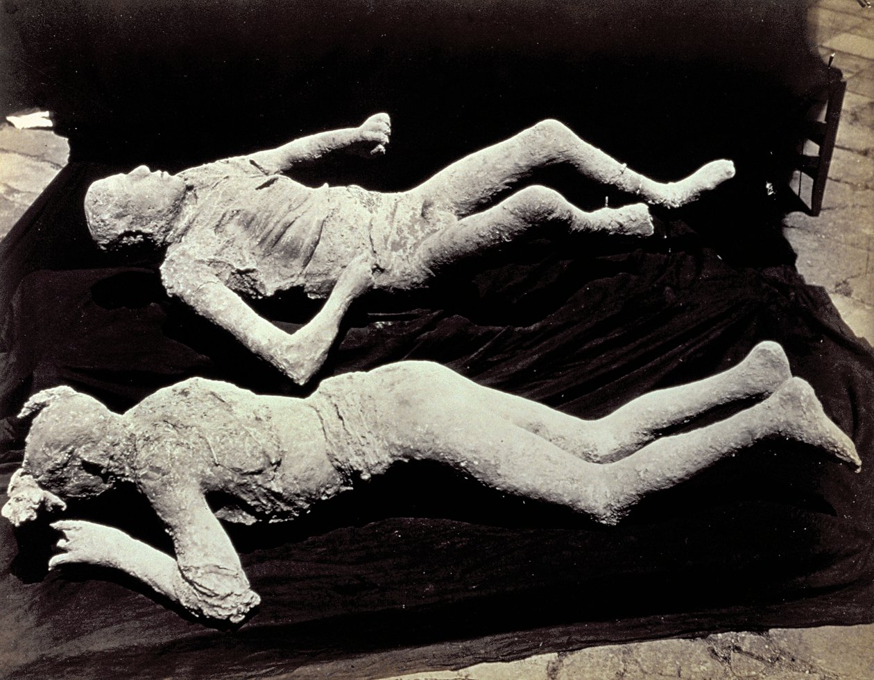 Två avgjutningar av människofigurer från utgrävningarna i Pompeji. Utställningarna placerades på svart tyg för att fotografera dem av Giorgio Sommer