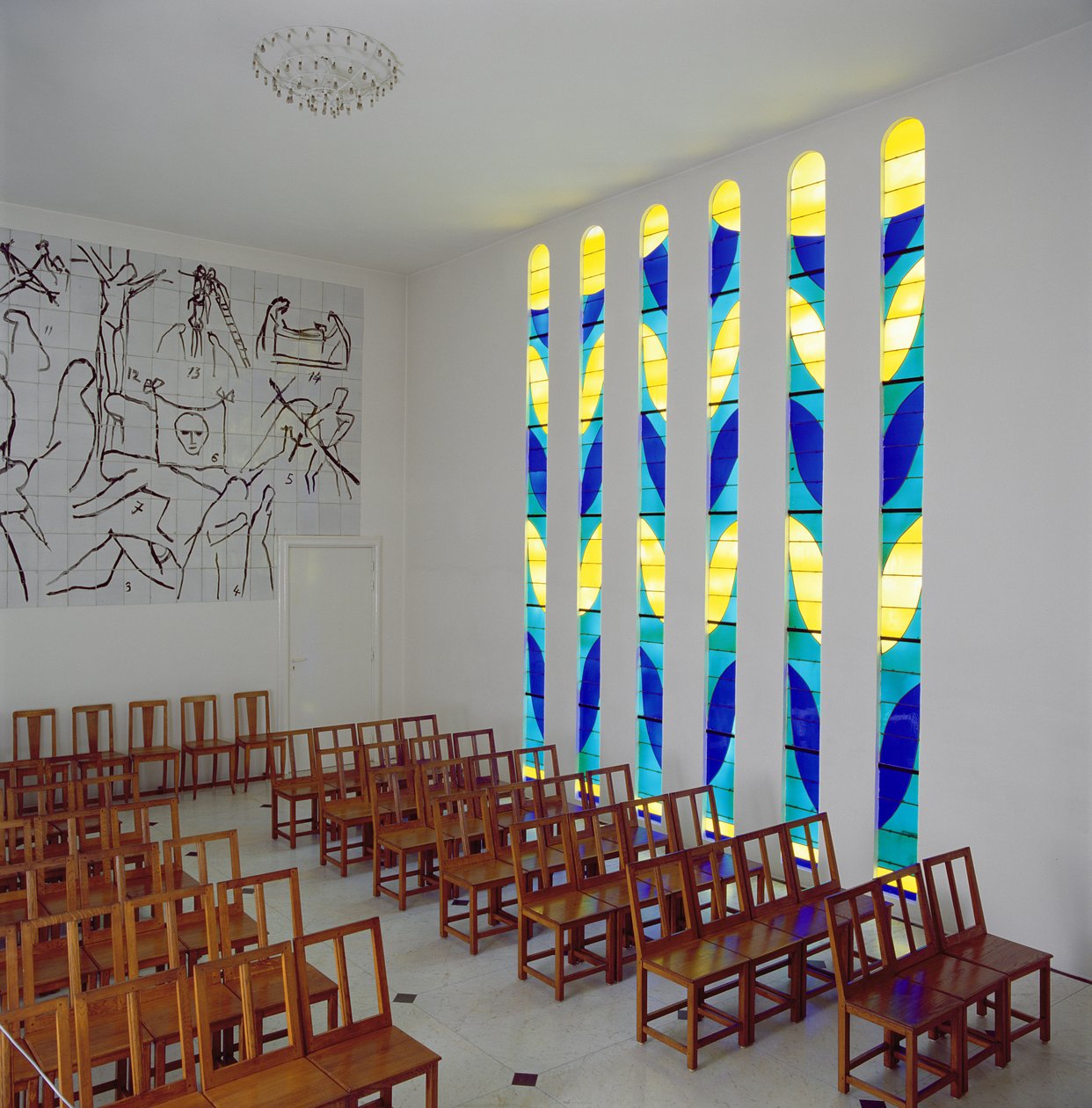 Vy över långhuset, sidofönstret med glasmålning och korsvägsstationen i Rosenkransens kapell, Vence av Henri Matisse