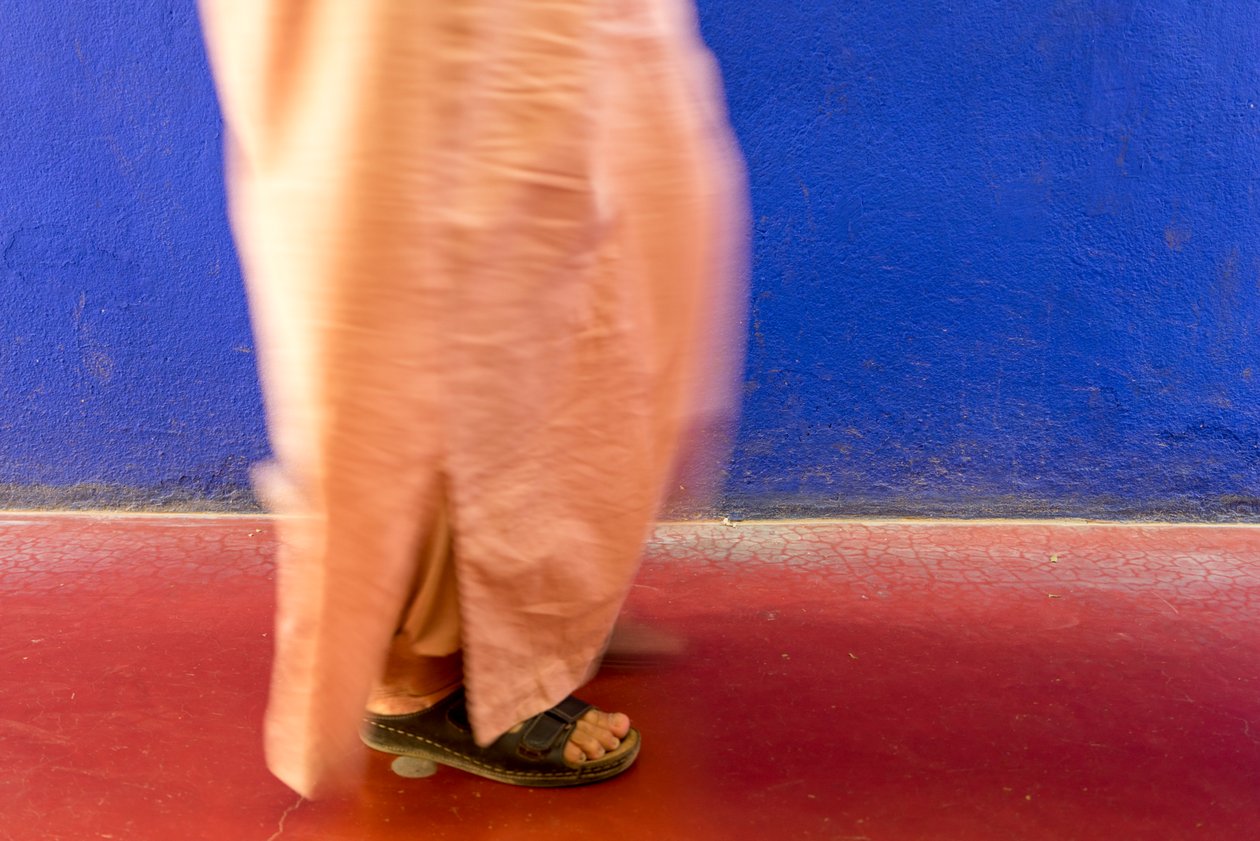 Går förbi en blå vägg i Majorelle-trädgården Jardin Majorelle i Marrakech, Marocko, 2014 (foto) av Ira Block