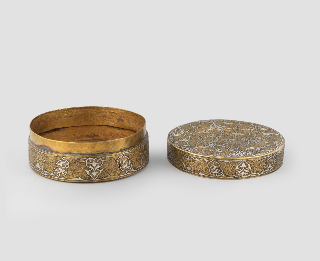 Ask med lock av cylindrisk form, av graverad mässing infälld med silver, med senare förgyllning och eventuellt tillägg av innerband, 1400-c.1525 av Iranian School