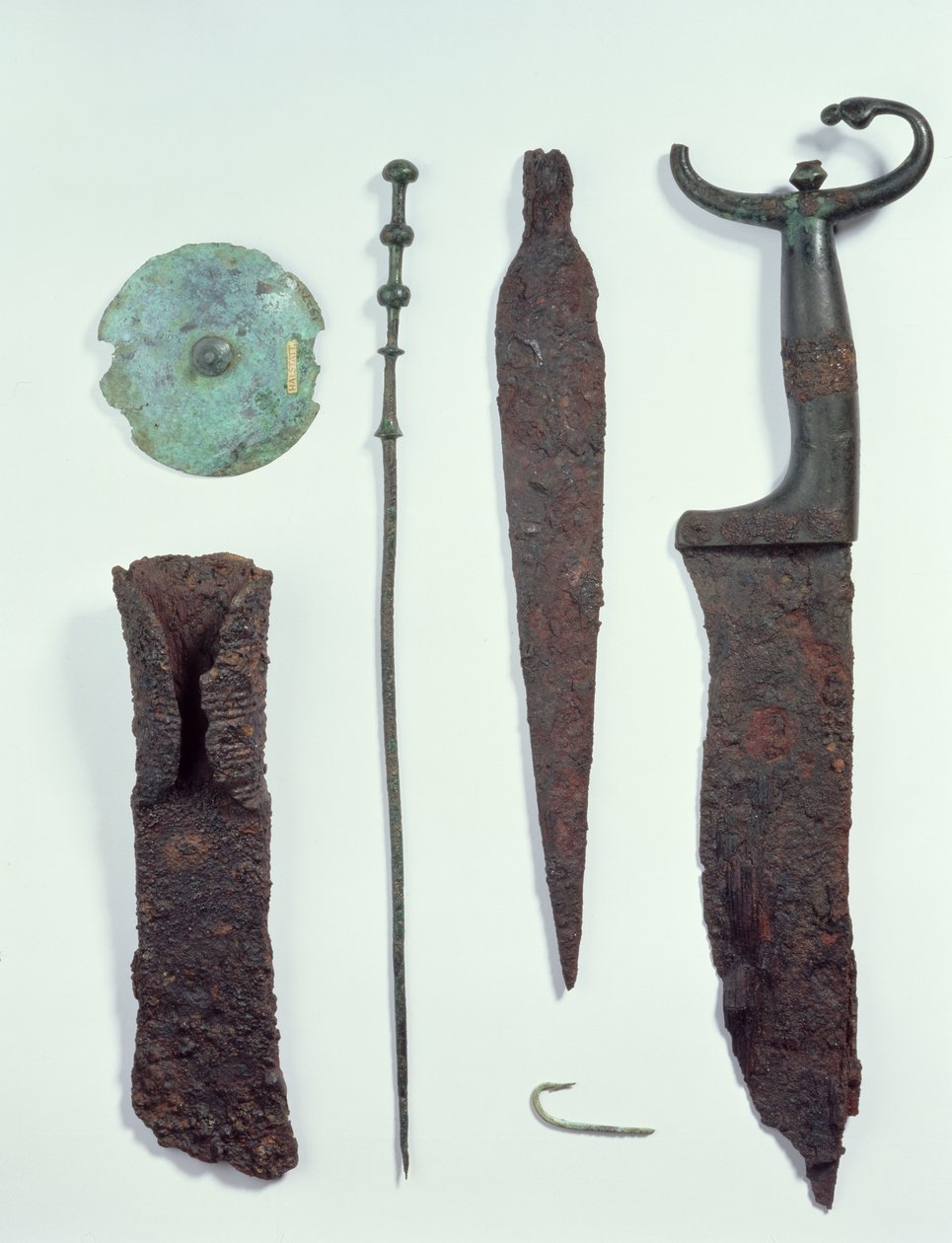 Uppifrån och ner: Kniv, spjuthuvud, fiskekrok, klädnål, bältesskiva och yxa, alla hittade i mansgravar i Hallstatt, järnålder. av Iron Age