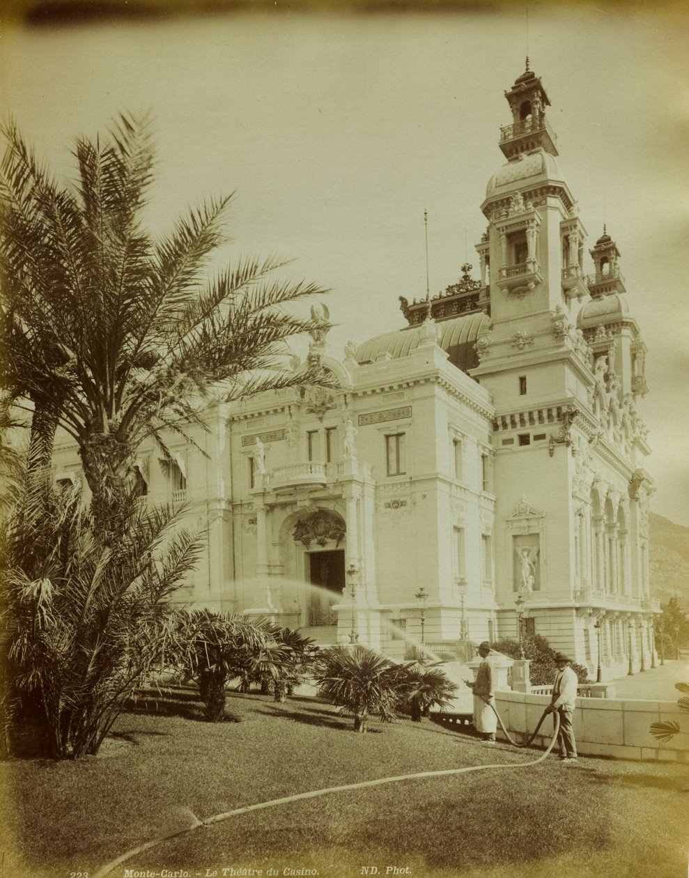 Teatern ansluten till kasinot i Montecarlo. I förgrunden utsikt över trädgården prydd med palmer av Italian Photographer