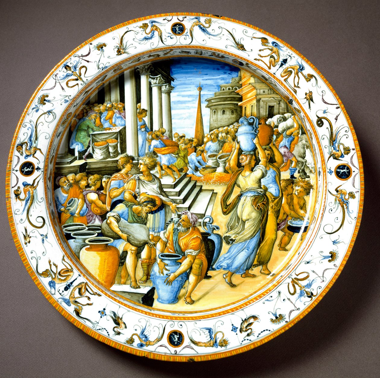 Ett congiarium (congiarium) i antikens Rom (gratis utdelning av vin, olja till folket) Keramisk tallrik tillverkad i Urbino i verkstaden Fontana, Italien. 1550 runt Florens, Museo Nazionale del Bargello - En kongiarie (kongiarium) i antikens Rom (gratis di av Italian School