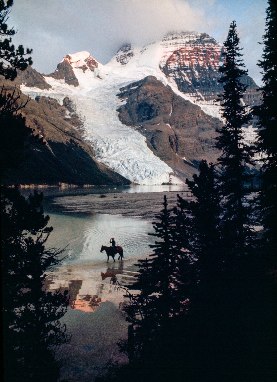 Ensam häst och ryttare speglar sig i sjön vid foten av Kanadas högsta bergstopp. Mount Robson... av James L Stanfield