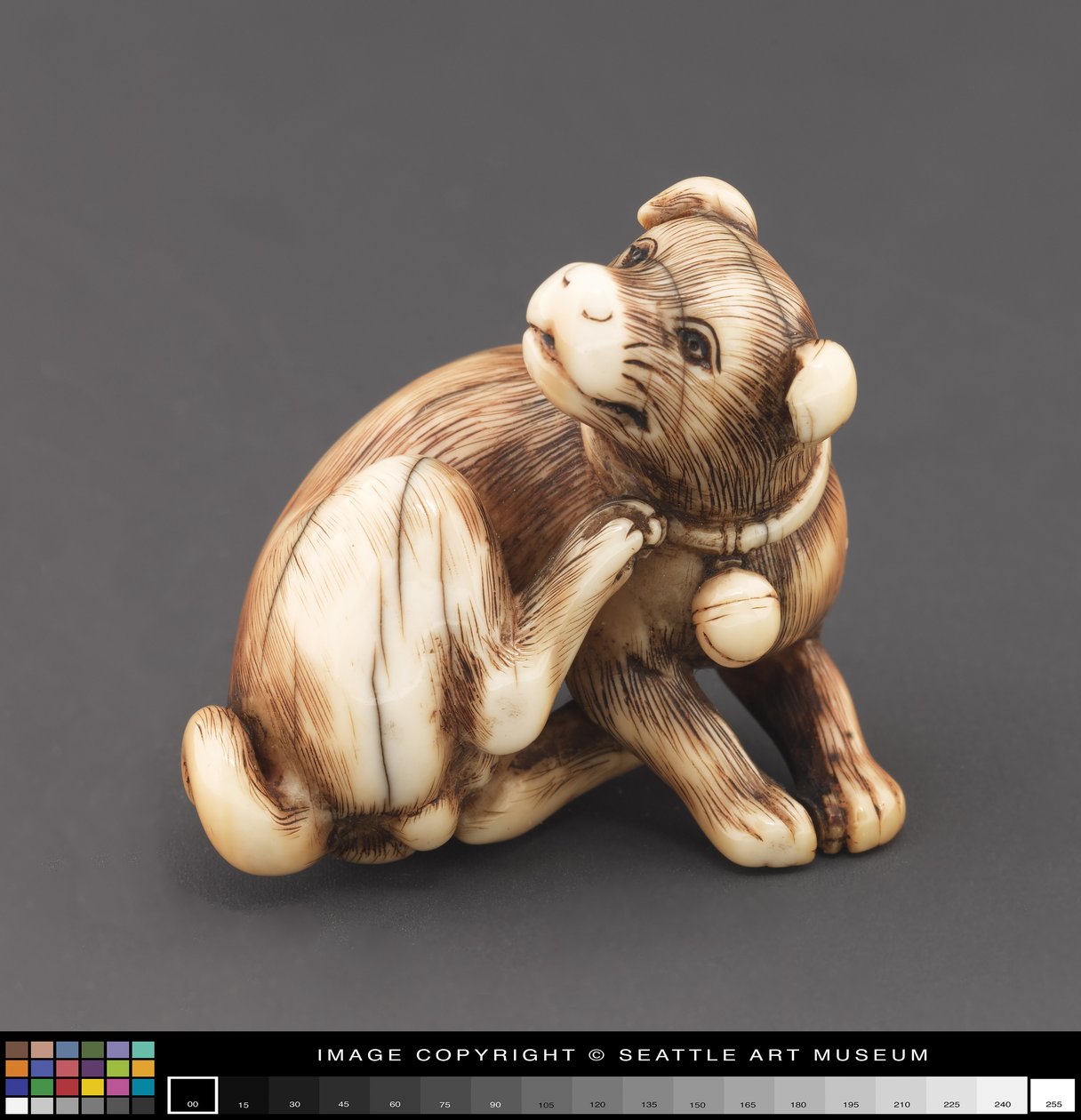 Netsuke modelleras som en hund som kliar sig nacke av Japanese School