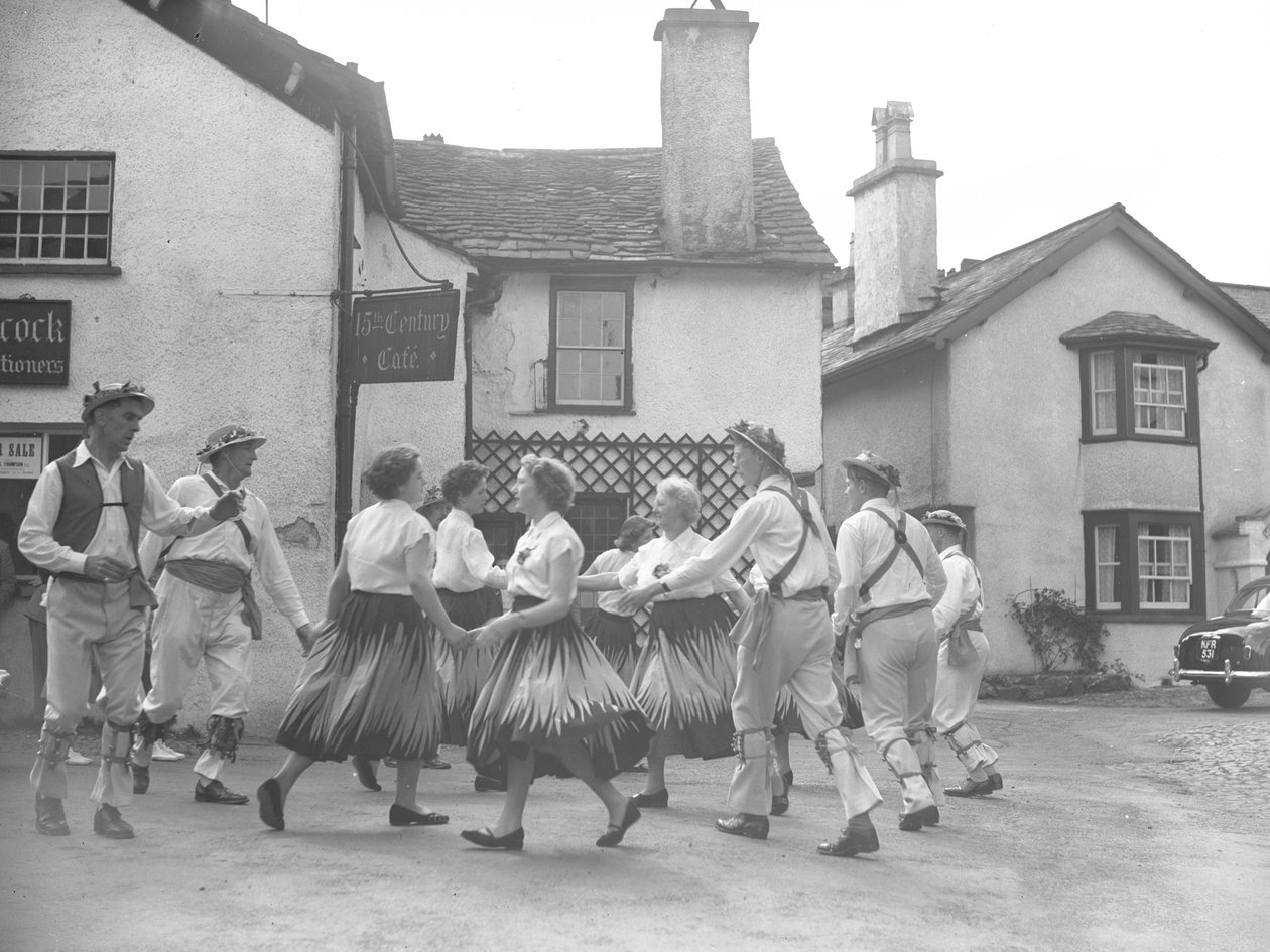 Män och kvinnor dansar på Hawkshead med skylt för "15 Century Café" bakom och auktionsförrättare av Joseph Hardman