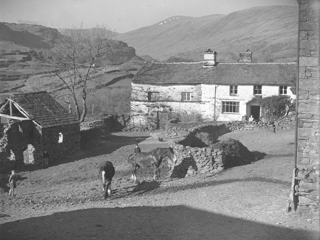 Tre unga pojkar tittar på hästar på gårdsplanen vid Kentmere med bondgård och fjäll bakom av Joseph Hardman