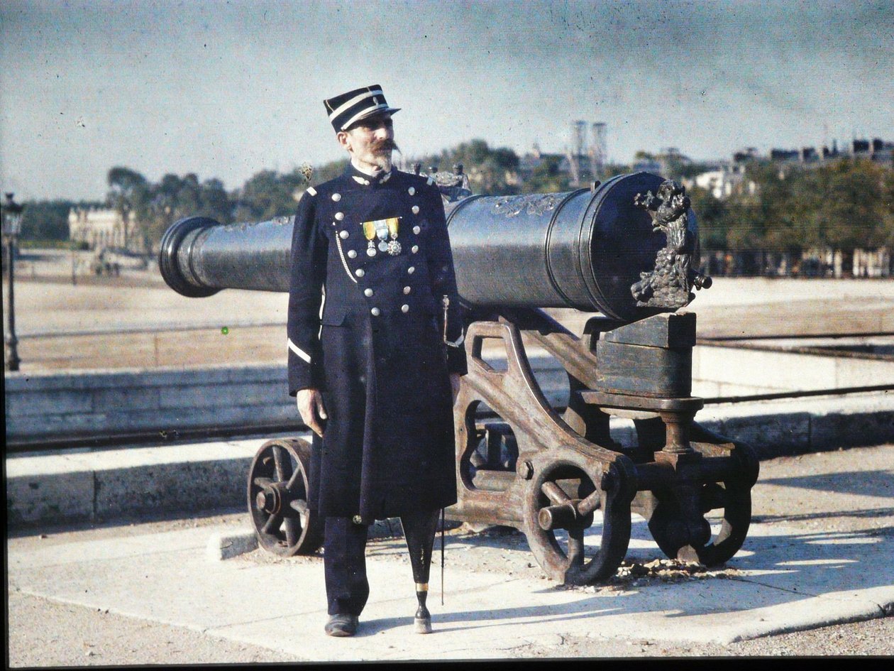 En soldat i uniform med tre medaljer står bredvid en kanon i Paris, 1918 (autokrom) av Jules Gervais Courtellemont