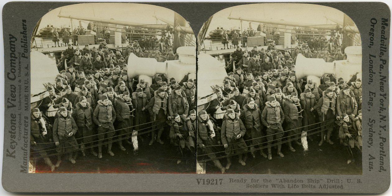 Horizontal, sepia stereocard showing uniformed American soldiers wearing life vests standing and sitting on the deck of a ship. Keystone Stereograph number V19217. The title reads av Keystone View Company