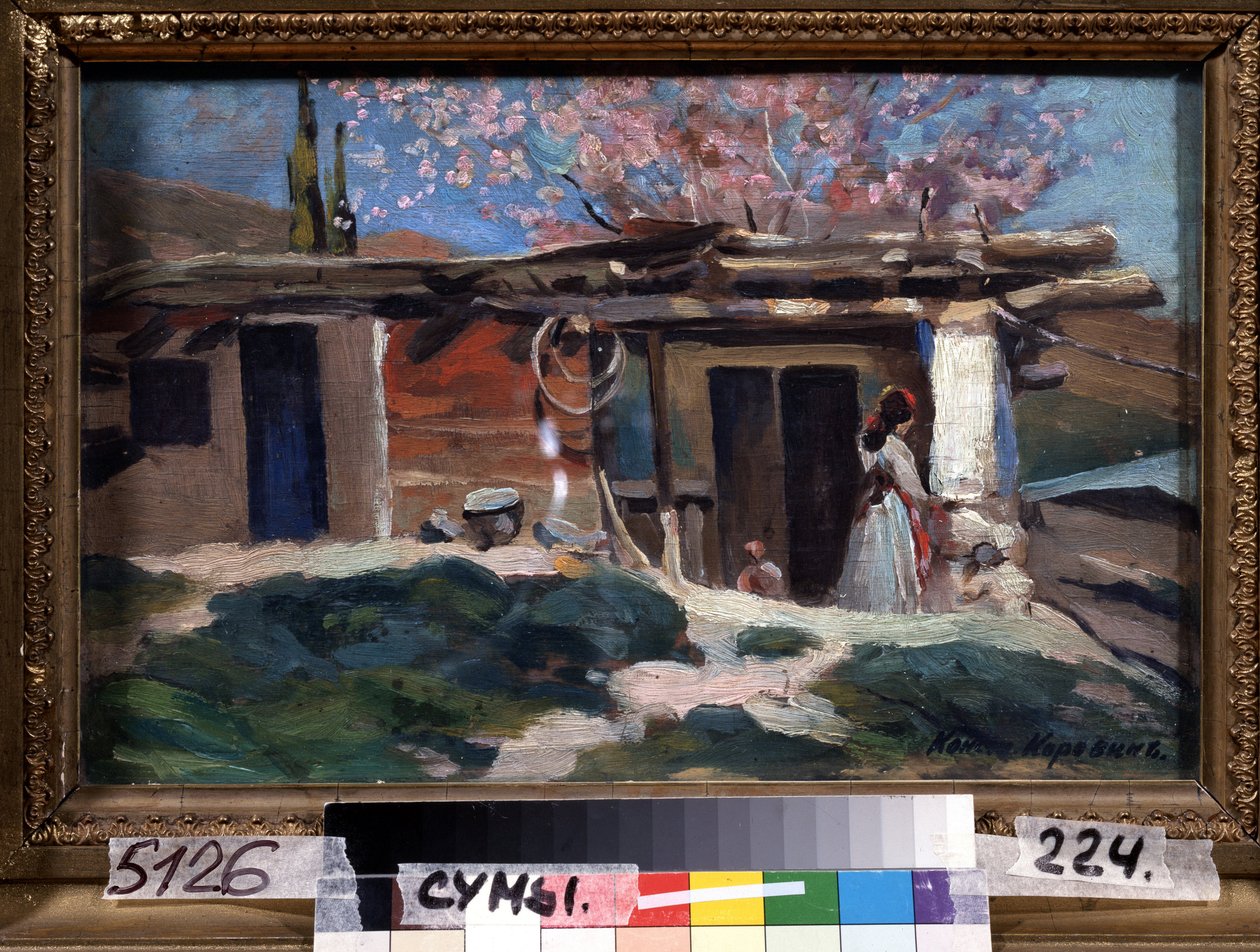 Krim, mandelträd i blom. (Krim, blommande mandelträd). Ung kvinna framför ett litet trähus, under rosa mandelträd. Målning av Konstantin Alexeyevich Korovin (Constantin Korovin) (1861-1939), olja på duk av Konstantin Alekseevich Korovin
