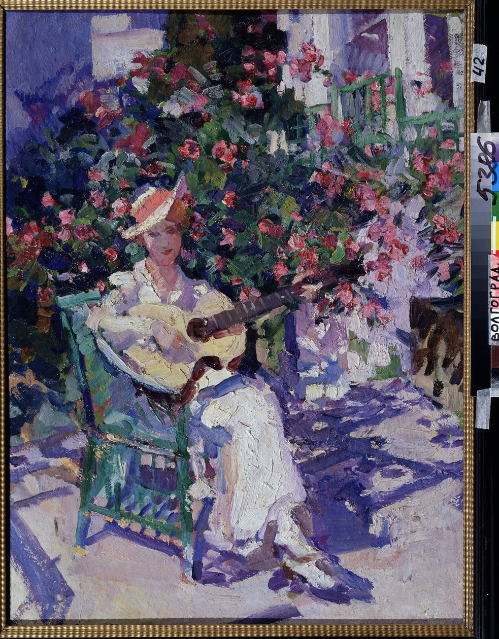 In Crimea (In the Crimea). En ung kvinna i en lätt, lätt klänning, som sitter på en trädgårdsstol, framför en blommande lund, spelar gitarr, mitt i sommaren i kustområdet vid Krimbukten. Målning av Konstantin Alexeyevich Korovin (Constan av Konstantin Alekseevich Korovin