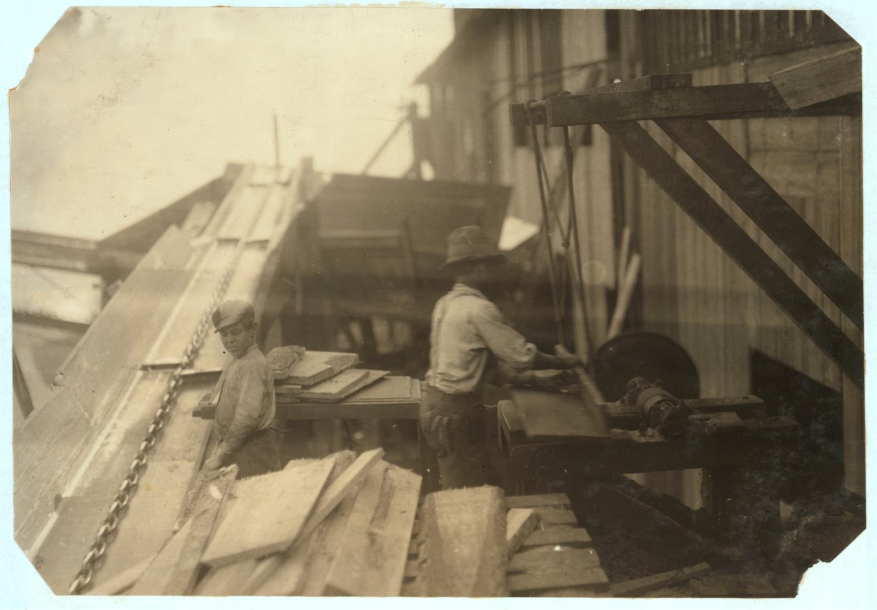 Charlie McBride, 12 år, tar ved från en ränna i 10 timmar hos Miller und Vidor Lumber Company, Beaumont, Texas, för vilken han tjänar 50 cent medan den andra pojken sågar det på en obevakad cirkelsåg, 191 av Lewis Wickes Hine