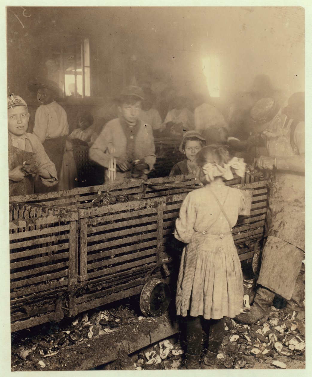 Fabriken Lowden Canning Company, Bluffton, South Carolina, med en 7-årig flicka som skivar 3 krukor ostron per dag tillsammans med sin 6-åriga bror och en 11-årig pojke som skivar 6 krukor, 1913 (svart på vitt). av Lewis Wickes Hine