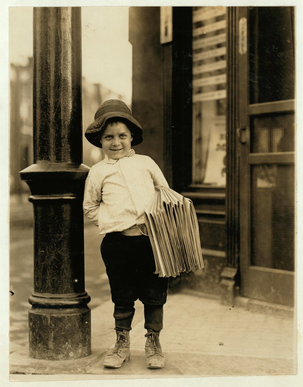 En sexårig tidningsbud, känd som Little Fattie och endast 1,5 meter lång, har arbetat i ett år i St. Louis, Missouri, 1910. av Lewis Wickes Hine