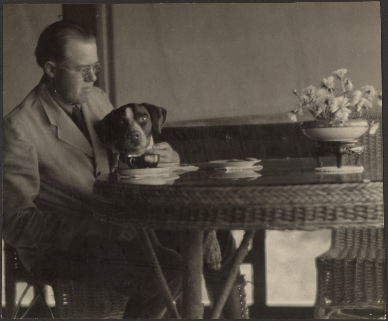 [Man och hund sitter vid ett bord] av Louis Fleckenstein