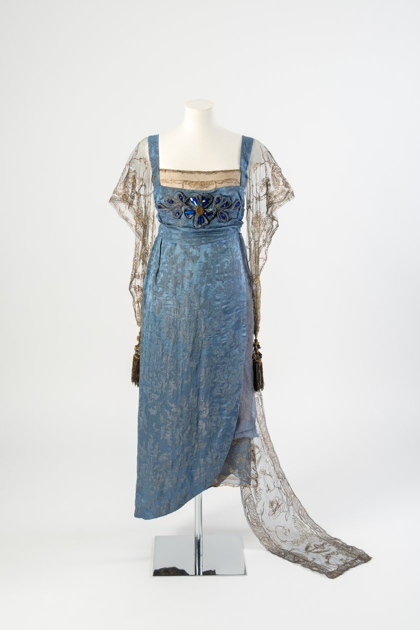 Aftonklänning i siden i blå figur med nätärmar och tåg i guld broderad i guldmetallremsa och dekorerad med blå ädelstenar och tofsar, 1911 (siden) av Lucy Christiana, Lady Duff Gordon