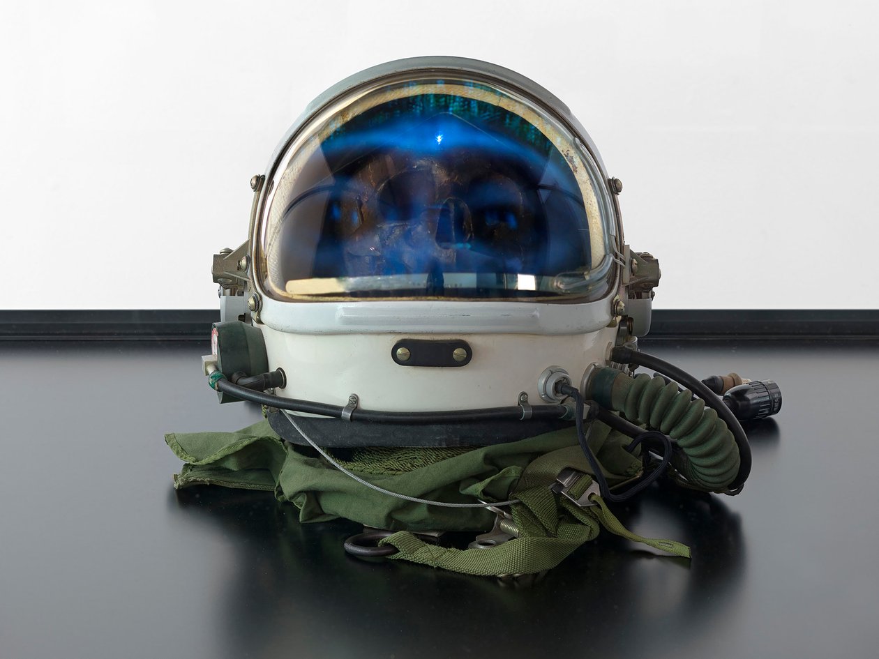 Alpha Omega, 2016 (Glas, LCD-skärm, mediaspelare, replikaskalle, rymdhjälm, trä) av Mat Collishaw
