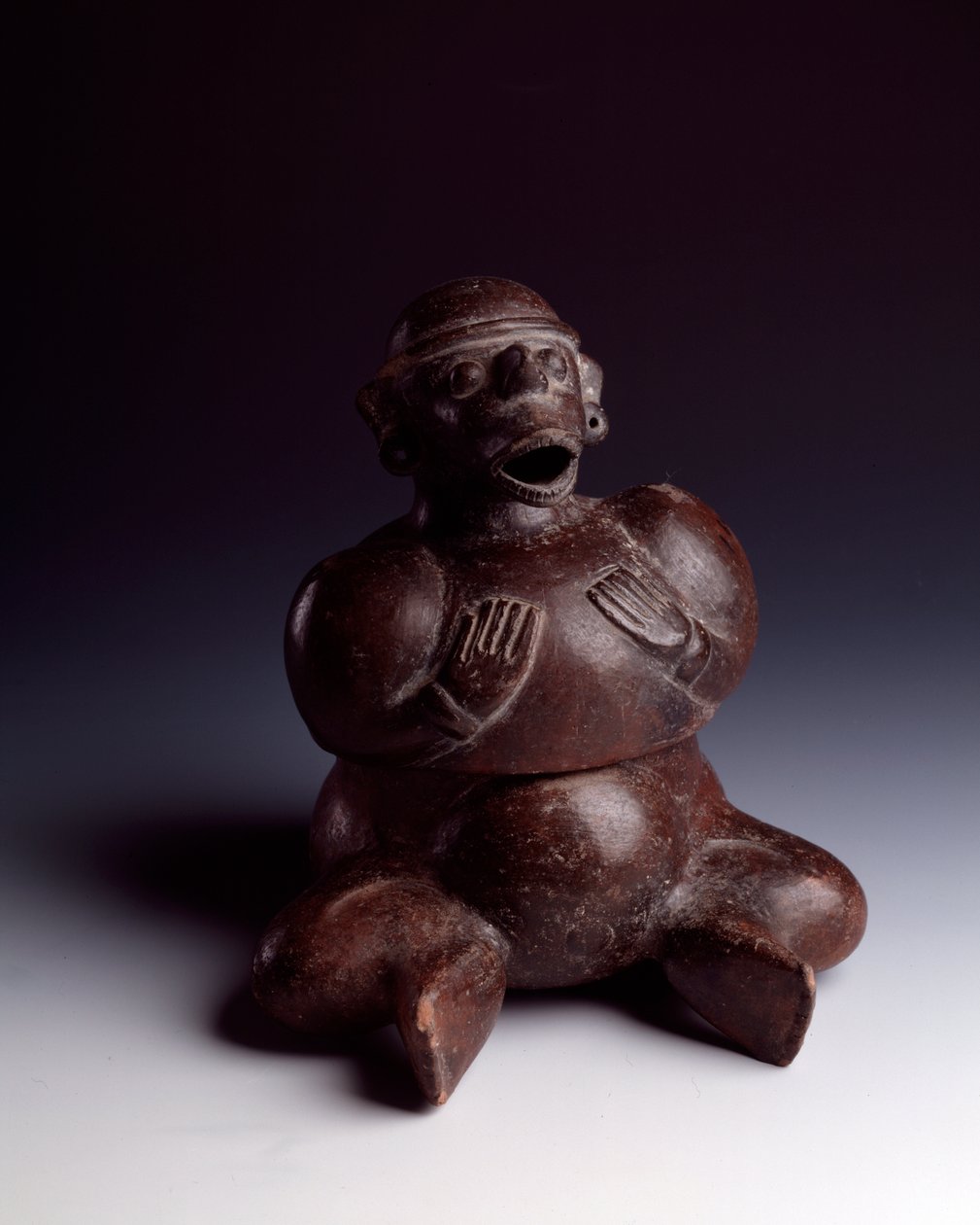 Precolombiansk konst, Maya-civilisation, inledande period: antropomorf lervas föreställande en man som sitter med händerna på bröstet och bär en apmask med öppen mun. Från Uaxactun, Guatemala. Sol. h. 22,5 x bredd 19 cm Guatemala, Museo Nazionale di Arc av Mayan Mayan