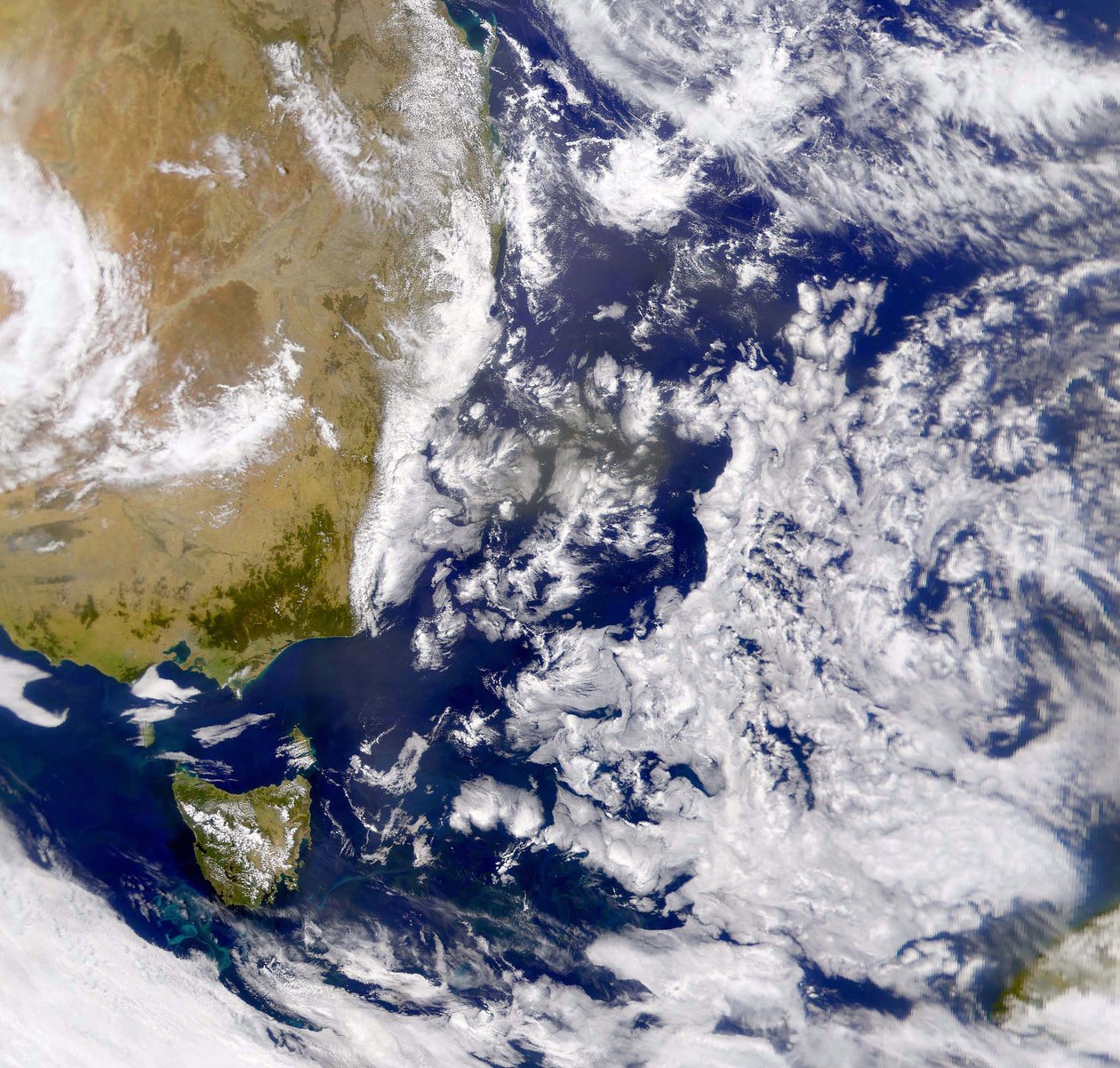 Satellitfoto av Tasmanhavet delvis täckt av moln. Till vänster är en del av Australien med Tasmanien under sig. NASA. Vetenskap av National Aeronautics and Space Administration National Aeronautics and Space Administration