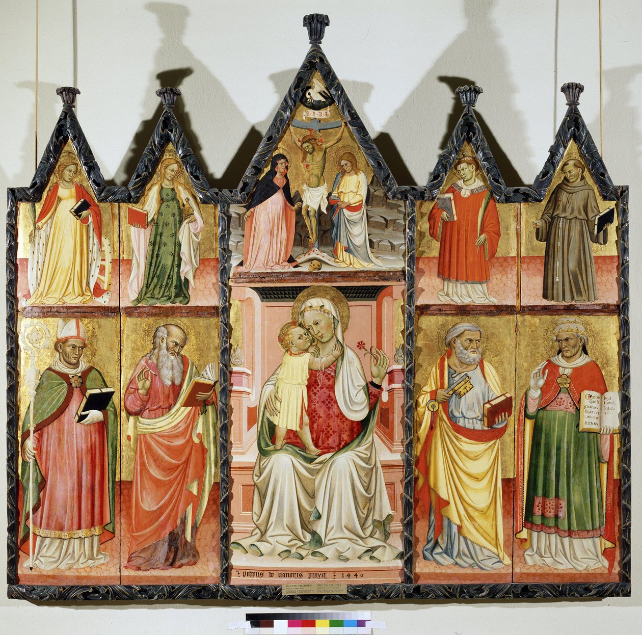 Polyptyk av jungfrun och barnet med heliga. Överst till vänster: Sankta Katarina av Alexandria och Sankta Maria Magdalena. I mitten runt Kristus på korset med inskriptionen ""INRI"" (I.N.R.I.). Jungfru Maria och Sankt Johannes. Överst till höger: S av Pietro di Giovanni Lianori