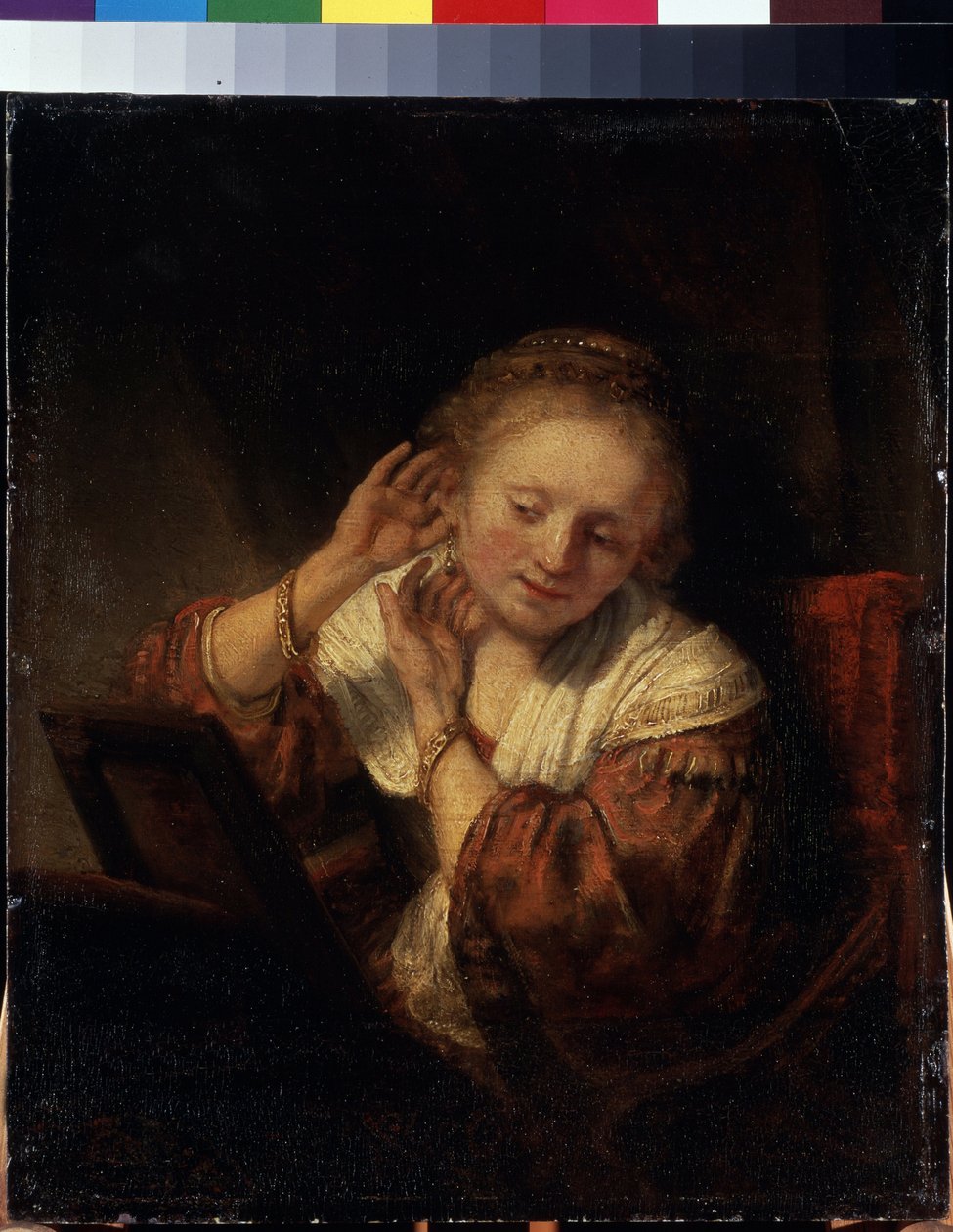 Ung kvinna som försöker på örhängen. Ung kvinna som försöker på örhängen. Målning av Harmenszoon van Rijn känd som Rembrandt (1606-1669) av Rembrandt Harmensz. van Rijn