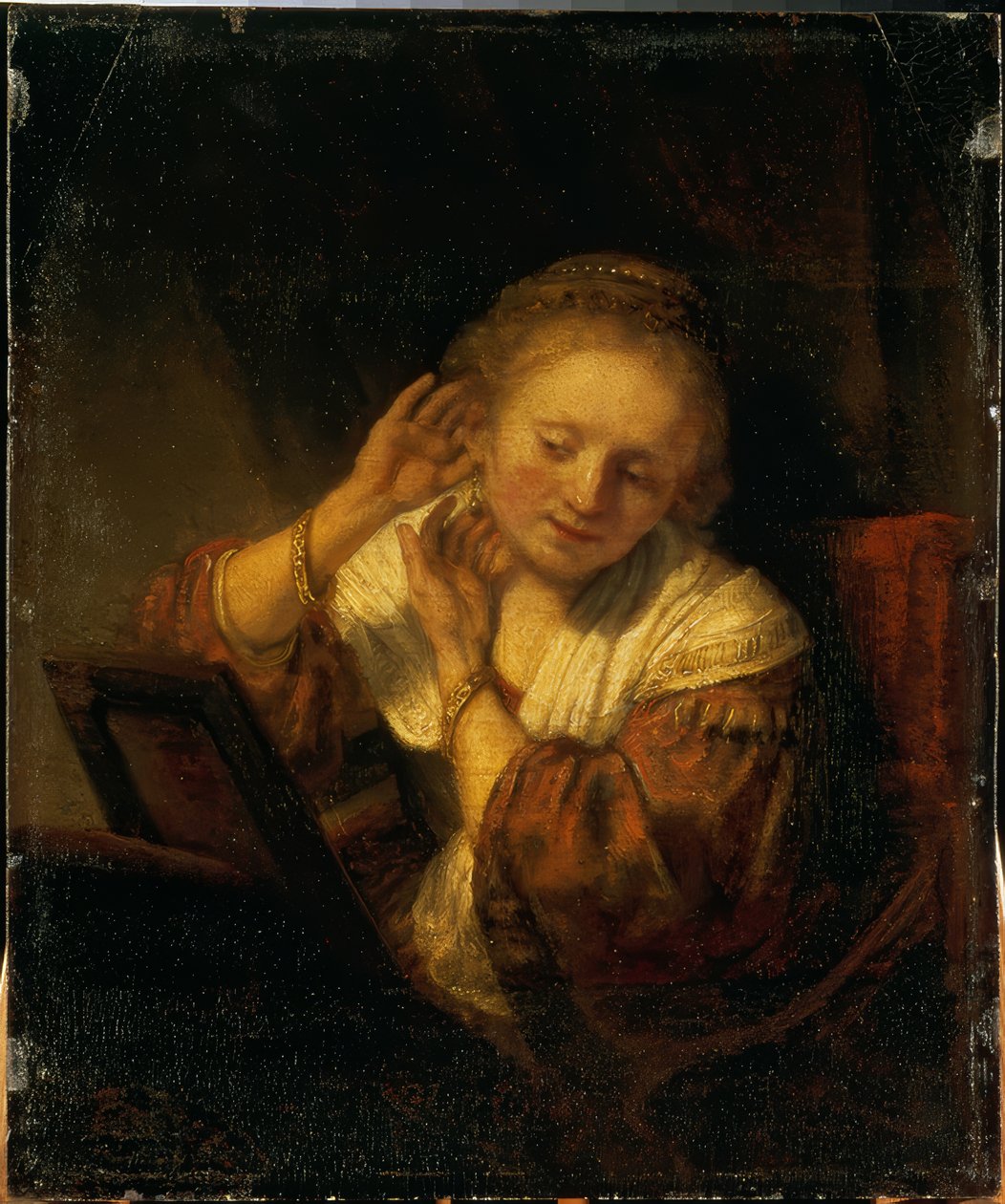 Ung kvinna som smyckar sig med örhängen av Rembrandt van Rijn