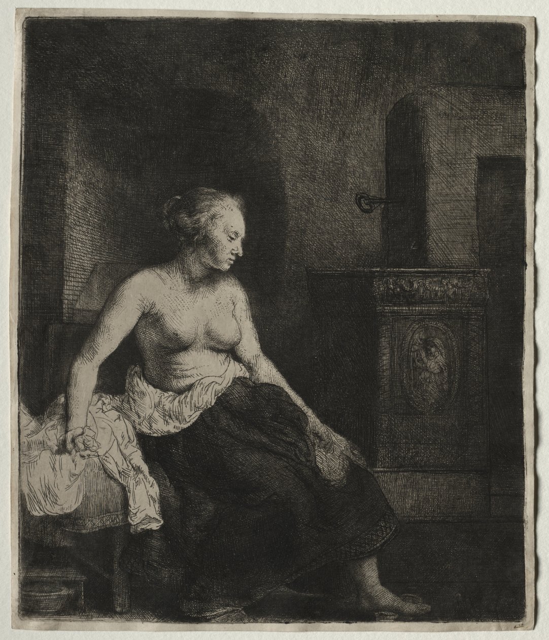 Kvinna som sitter halvt klädd bredvid en spis av Rembrandt van Rijn