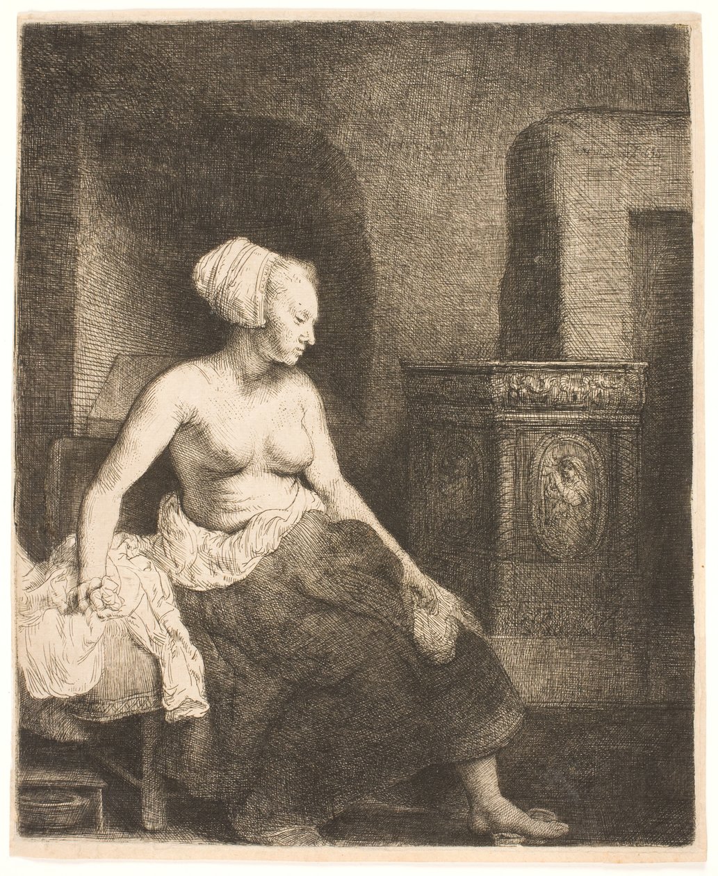Kvinna som sitter halvklädd bredvid en spis av Rembrandt van Rijn