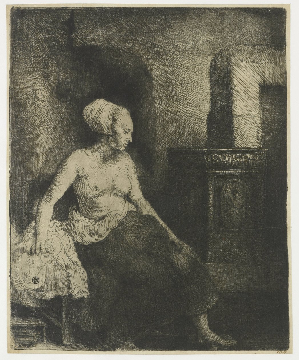 Kvinna som sitter halvklädd bredvid en spis av Rembrandt van Rijn