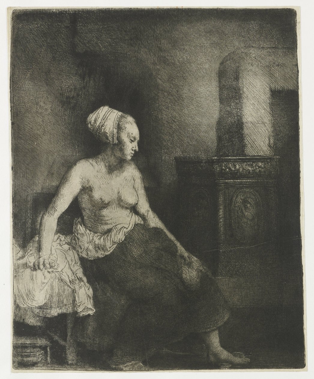 Kvinna som sitter halvklädd bredvid en spis av Rembrandt van Rijn