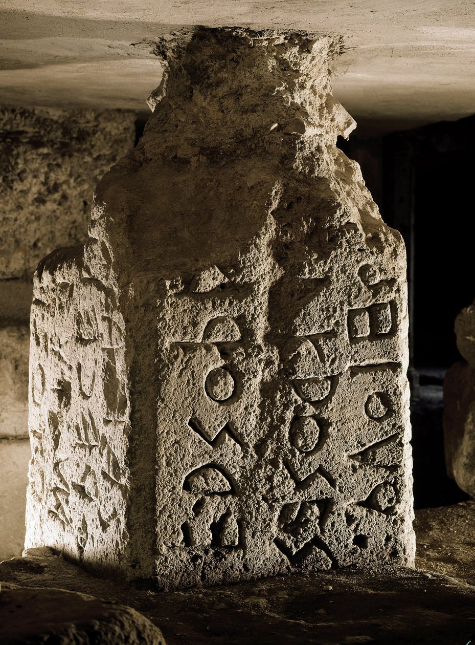Borne (eller cippe) av Forum Romanum (Foro Romano) som finns under bågen av Septime Severe. Graverad inskription på latin. 600-talet f.Kr. Rom, Forum Romanum - Stele (cippus) med graverad text på latin av en helig lag, från Lapis Niger. Sten, 600-talet av Roman