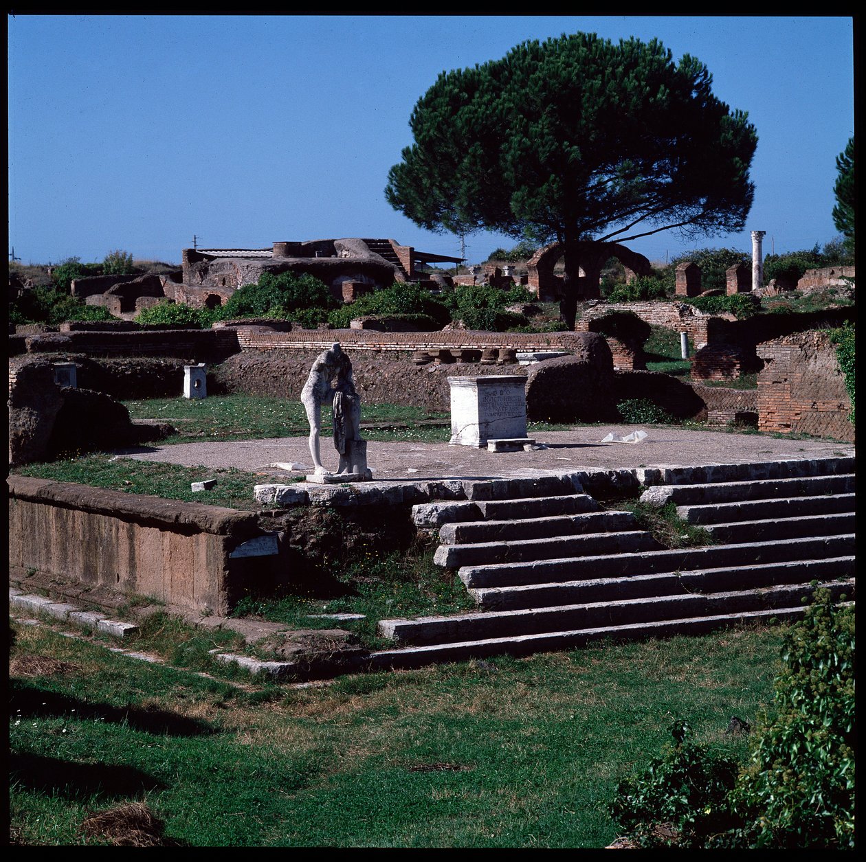 Romersk konst: utsikt över ruinerna av Herkulestemplet och statyn av Gaius Cartilius Popplicola, medborgare i Ostia av Roman