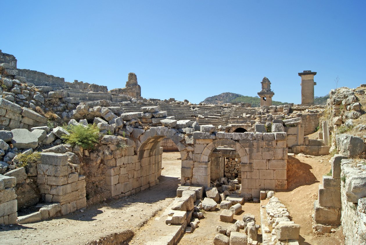 Utsikt genom den välvda ingången till Xanthos-teatern in i orkestergropen, med pelare och harpygrav, Xanthos, Turkiet (foto) av Roman
