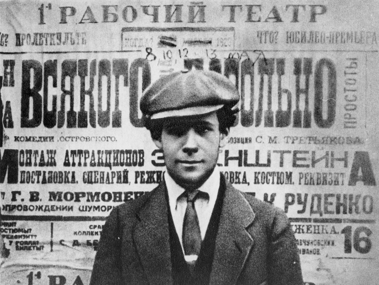 Sergei Eisenstein (1898-1948) framför en affisch för pjäsen, Sagesse, 1923, från Serge Eisenstein, Reflexions dun Cineaste, publicerad i Moskva, 1958 av Russian Photographer